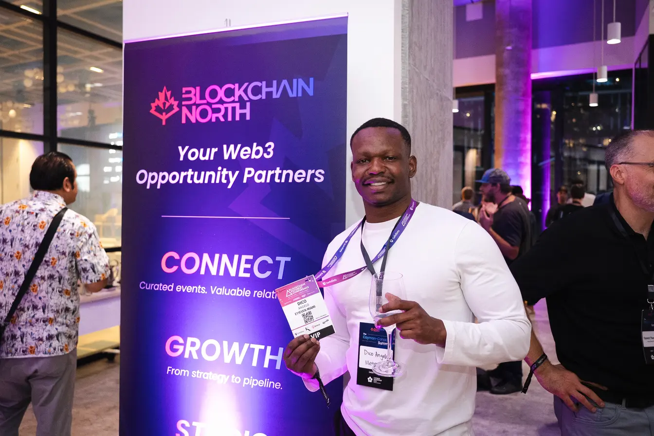 Dico beside a Blockchain North banner in amethyst-coloured light